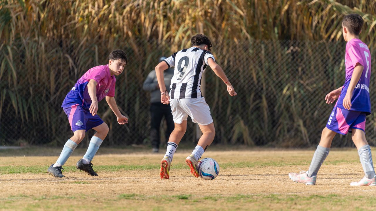 Youth soccer game with players in action outdoors, competing on a grassy field.