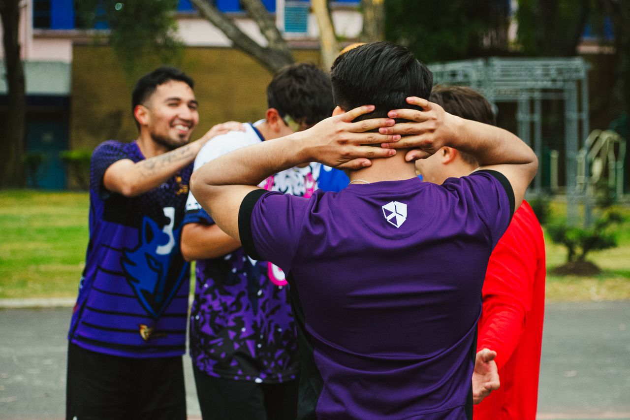 A group of young men in sports attire socialize in an outdoor setting in Mexico City.