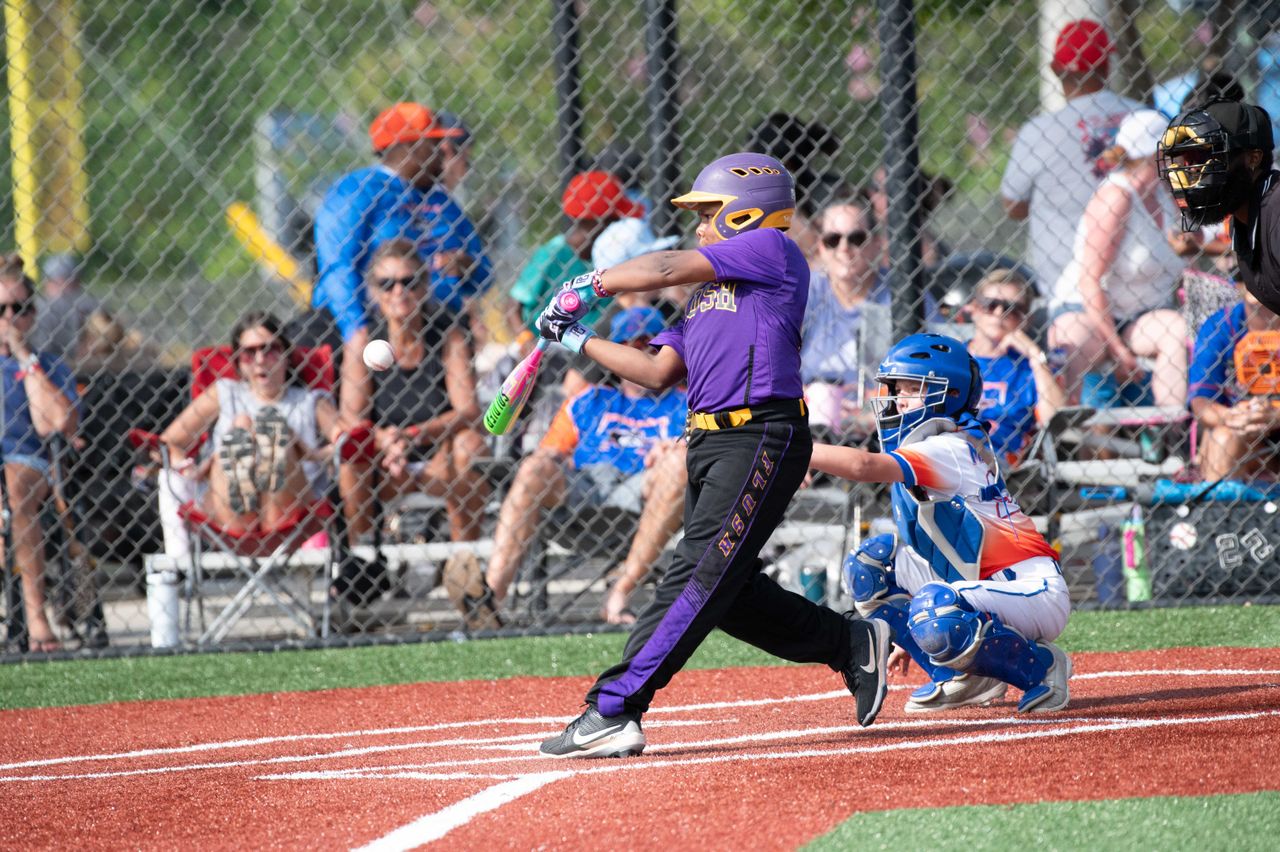 Young players engaged in a baseball game at a sunny outdoor park.